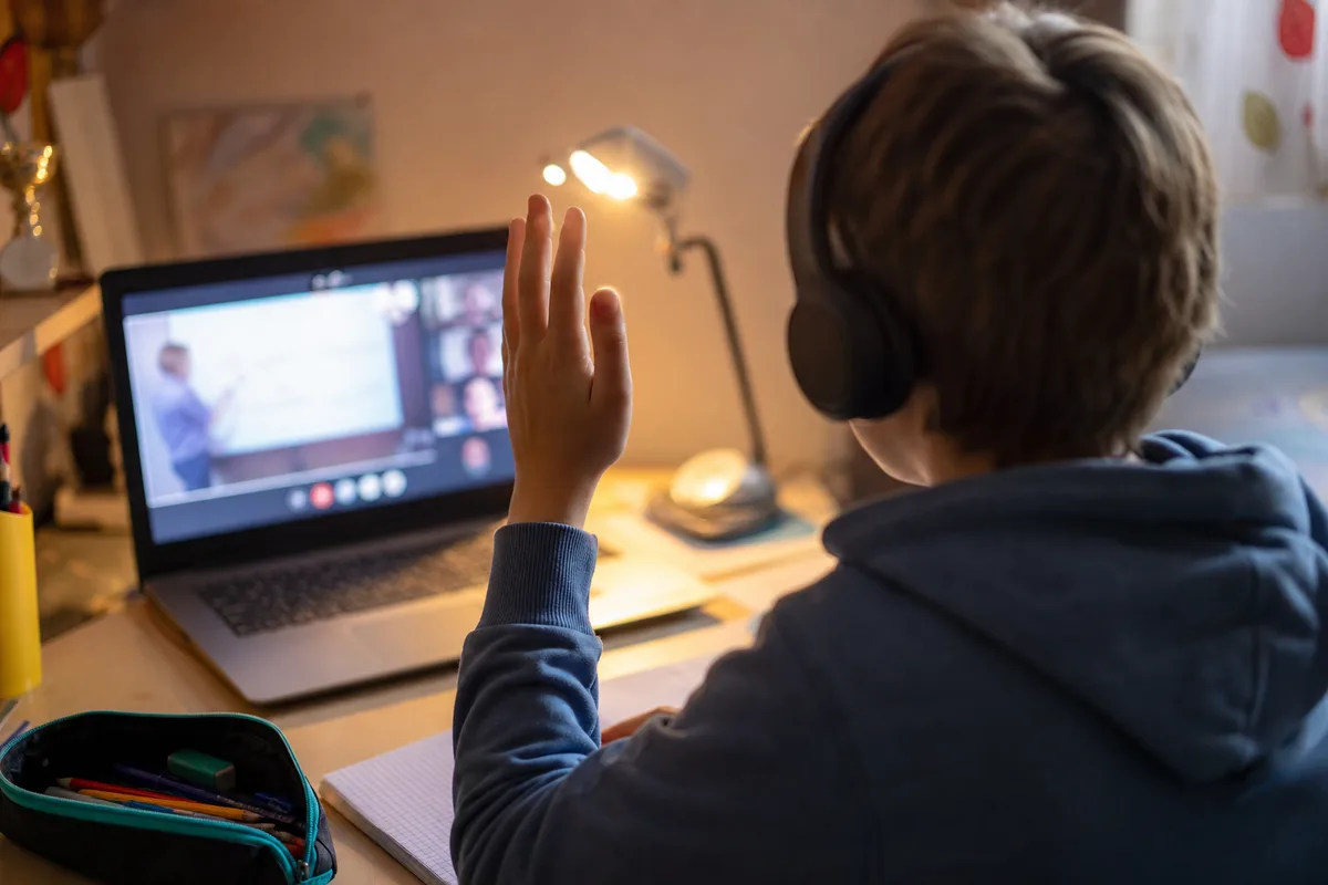 Enfant suivant un cours particulier en ligne avec un casque devant un ordinateur portable