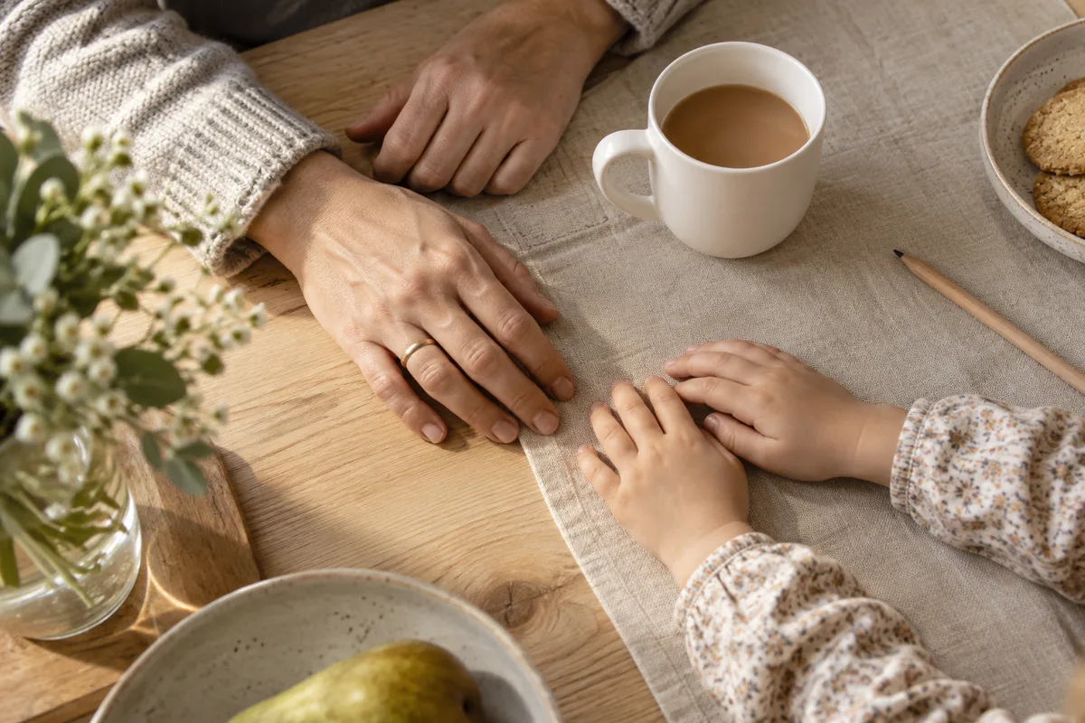 Mains d&rsquo;un adulte et d&rsquo;un enfant côte à côte près d&rsquo;une tasse blanche